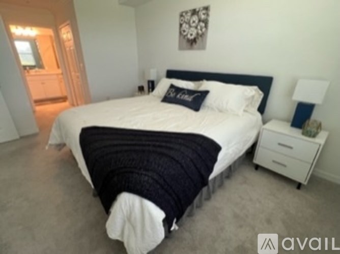 A bedroom with a large bed and a white nightstand.