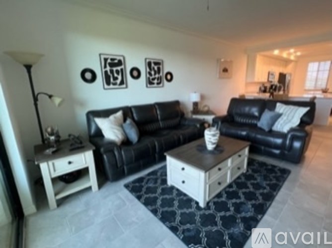 A black couch with a white coffee table in front of it.
