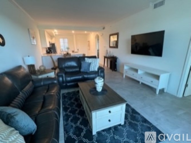 A living room with a black leather couch and a wooden coffee table.