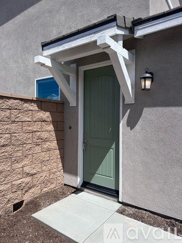 A green door is on the right side of a white wall.