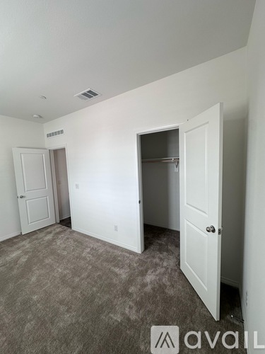 A room with carpeted floor and three doors.