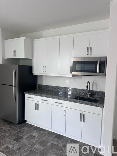 A kitchen with white cabinets and a black fridge.
