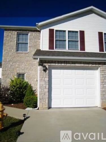 A house with a white garage door and a stone wall.