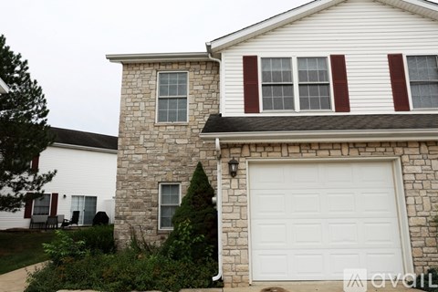 A house with a white garage door and a stone wall.