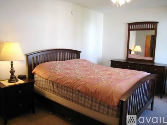 A bedroom with a bed, nightstand, and a dresser with a mirror.