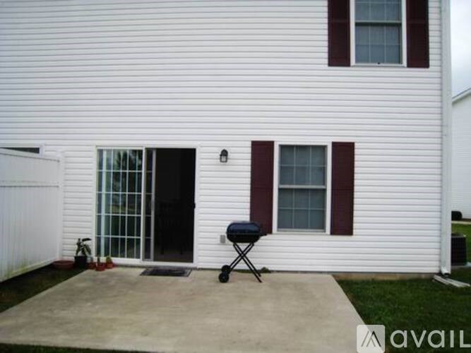 A white house with a black grill on the concrete patio.