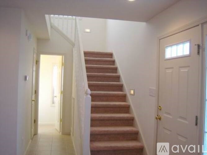 A staircase with a white railing leads to a door.