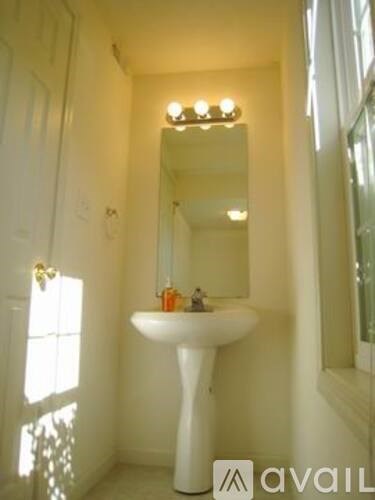 A white pedestal sink with a mirror above it.