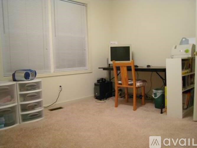 A room with a desk, chair, and computer monitor.