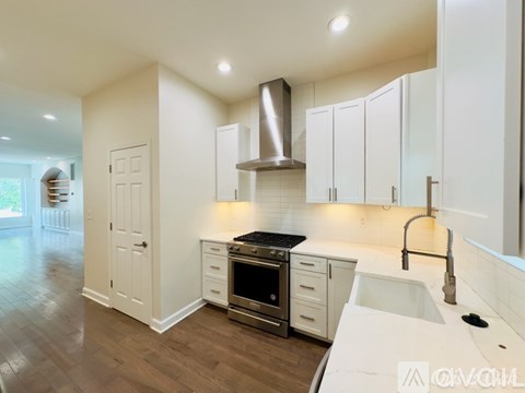 A modern kitchen with white cabinets and a stainless steel range hood.