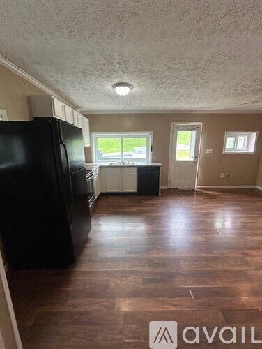 A kitchen with a black fridge and wooden floors.