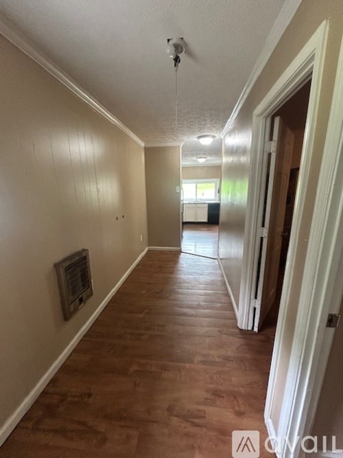 A long hallway with wood floors and white walls.