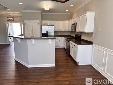 A kitchen with white cabinets and a black countertop.