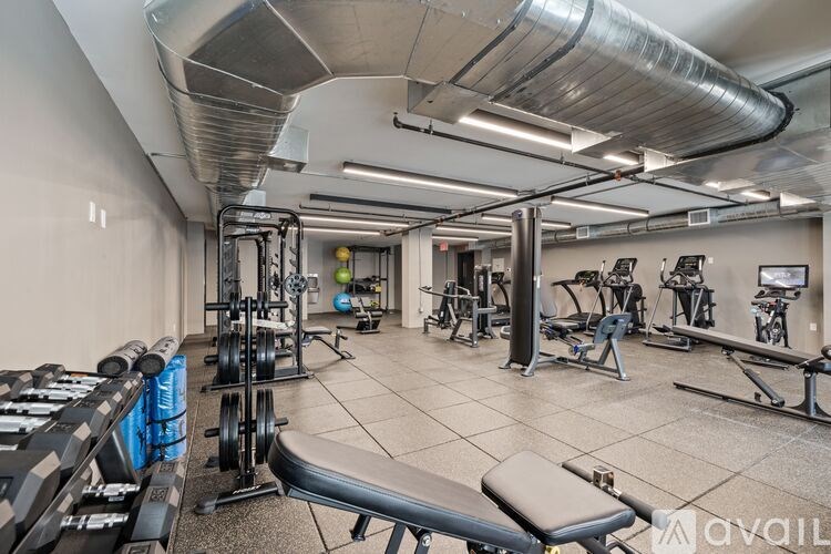 A gym with a variety of equipment including weights and benches.