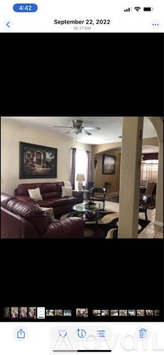 A living room with a red couch and a ceiling fan.
