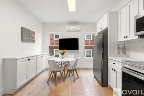 A modern dining room with a white table and chairs, a television, and a painting on the wall.