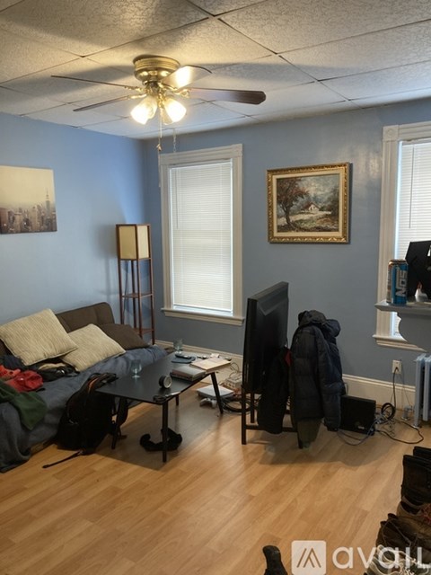 A living room with a couch, a table, a television, and a painting on the wall.