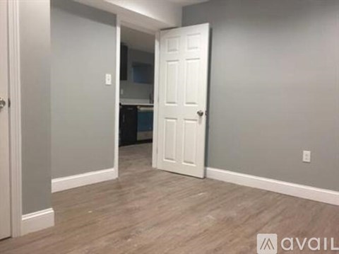 A room with a white door and a wooden floor.