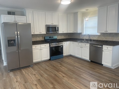 A kitchen with white cabinets and a wooden floor.