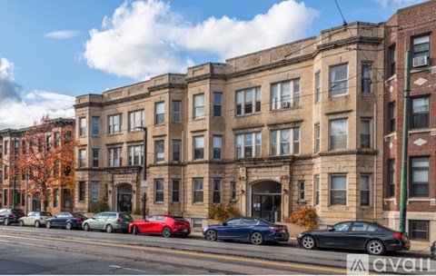 A row of cars parked on the side of a street in front of a large building.