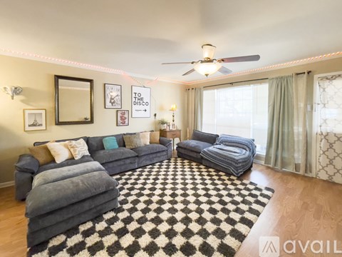 A living room with a grey couch and a black and white checkered rug.