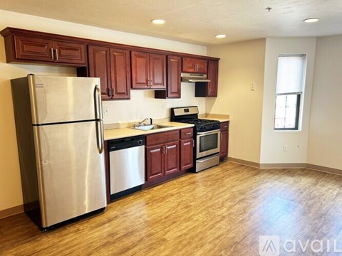 A kitchen with wooden cabinets and a stainless steel refrigerator.