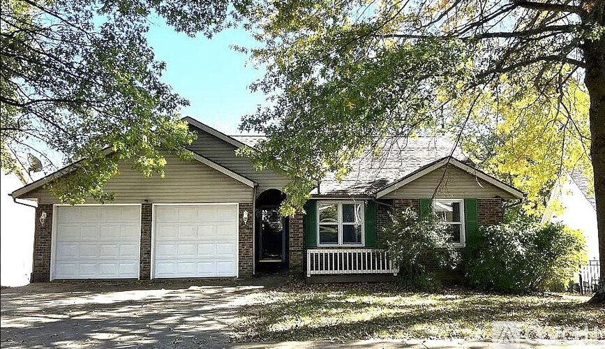 A house with a green front porch and white garage doors.