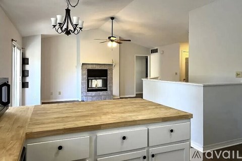 A kitchen with a wooden counter top and a chandelier hanging from the ceiling.