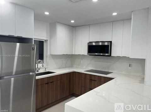 A modern kitchen with white cabinets and a stainless steel refrigerator.
