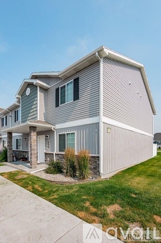 A modern house with a grey exterior and a well-maintained lawn.