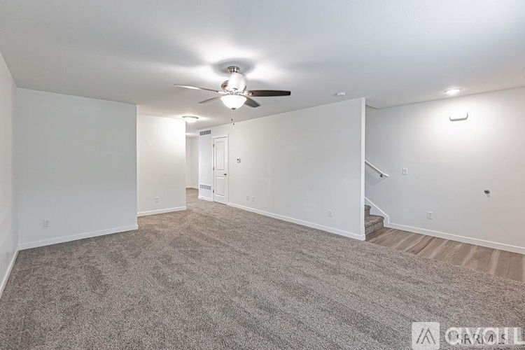 A spacious room with a ceiling fan and carpeted floor.