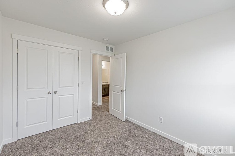 A bedroom with a carpeted floor and two doors.