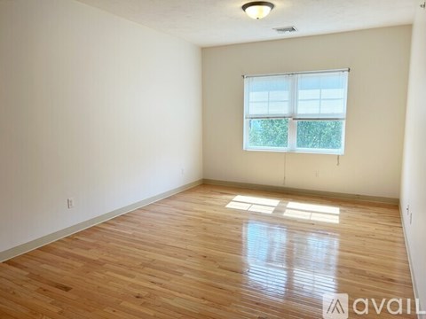 A room with wooden flooring and a window with blinds.