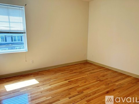 A room with wooden flooring and a window letting in natural light.