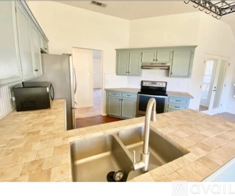 A kitchen with a sink, refrigerator, and microwave.