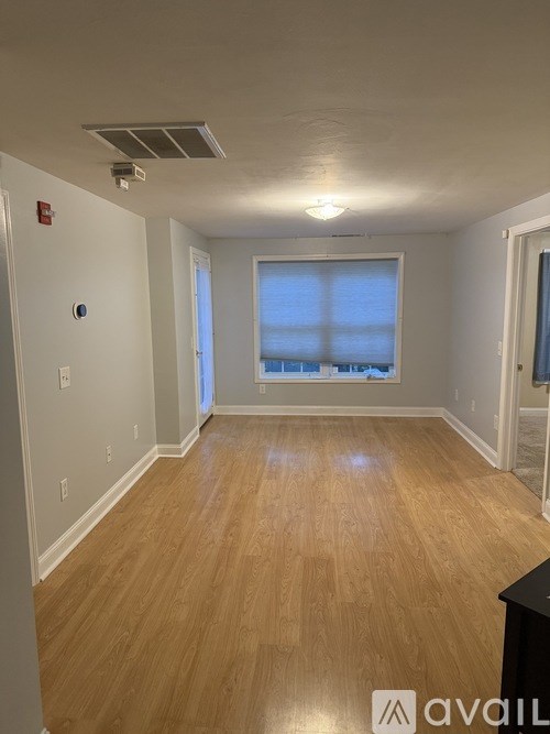 A room with wooden flooring and a window with blinds.