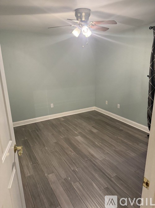 A room with a ceiling fan and light fixture, and a wooden floor.