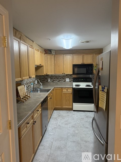 A kitchen with wooden cabinets and a refrigerator.
