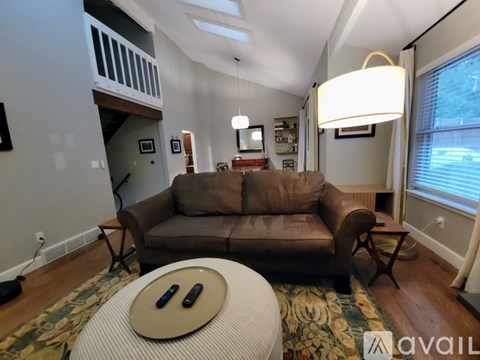 A living room with a brown couch and a round table with two bottles on it.