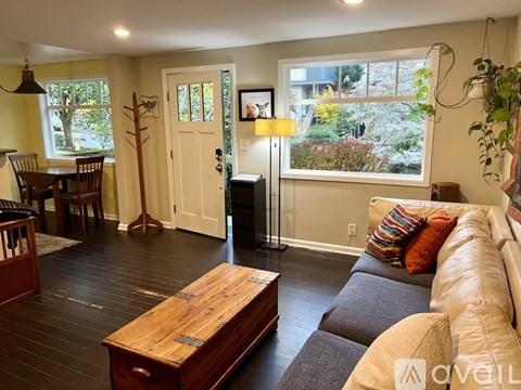 A living room with a brown wooden coffee table and a grey couch with orange and green pillows.