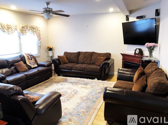 A living room with a brown leather couch and a flat screen TV mounted on the wall.