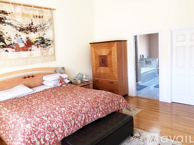 A bedroom with a large bed and a wooden cabinet.