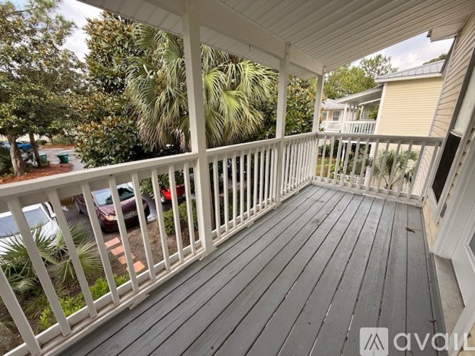 A wooden deck with a white railing and a view of a residential area.