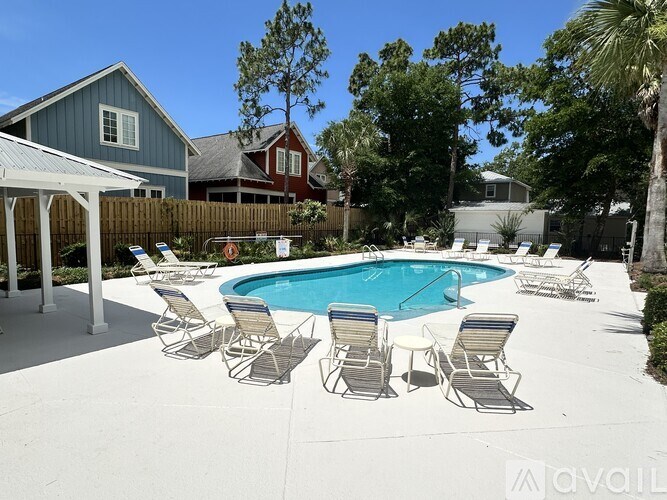 A pool surrounded by chairs and a fence.