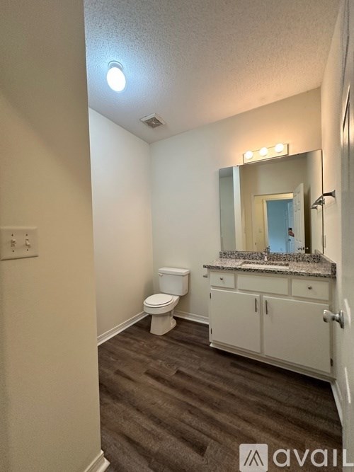 A bathroom with a toilet, sink and mirror.