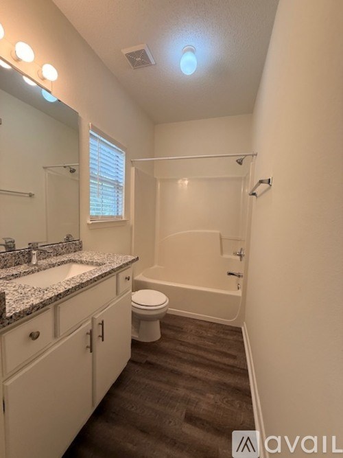A spacious room with wooden flooring and a ceiling fan.