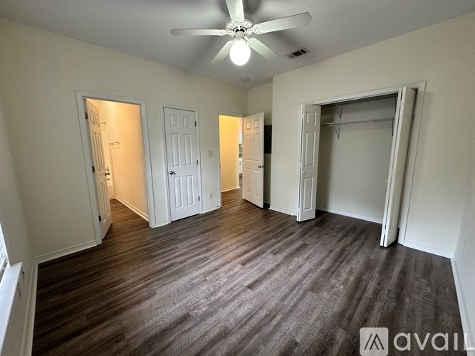A room with a ceiling fan and wooden flooring.