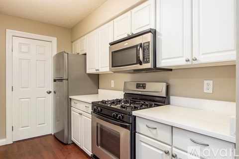 A kitchen with white cabinets and a black microwave above the stove.