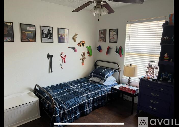 A bedroom with a bed, dresser, and a ceiling fan.
