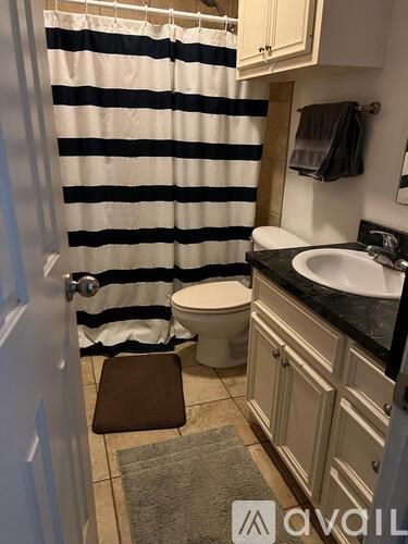 A bathroom with a toilet, sink, and striped shower curtain.